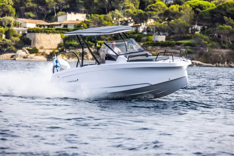 Slide: The Image of An Axopar 25 Cross Top boat speeds on the water, surrounded by scenic coastal landscape. - 2