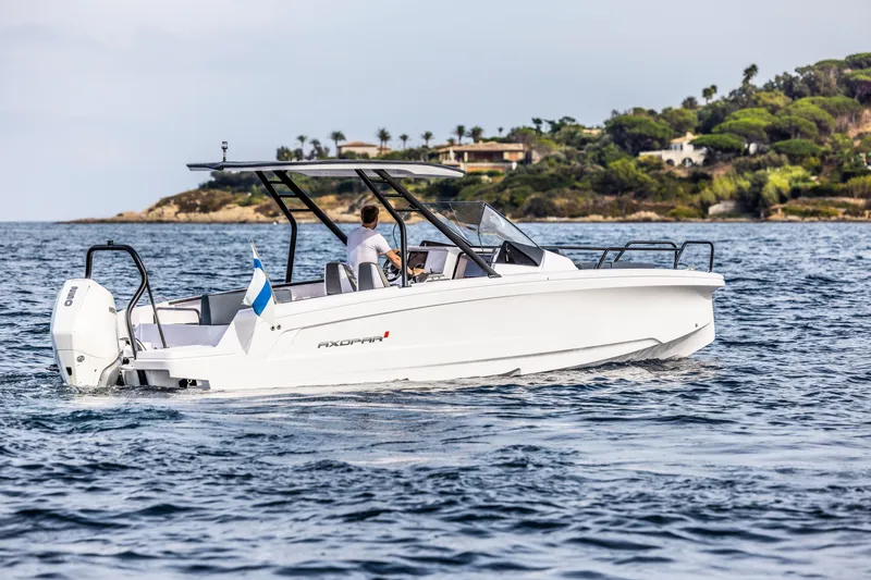 Slide: The Image of A 2023 Axopar 25 Cross Top boat cruising on calm water near a coastline. - 21