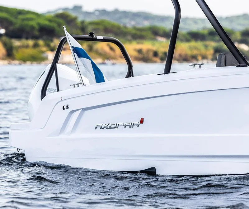 Slide: The Image of A 2023 Axopar 25 Cross Top boat on the water with a flag at the stern. - 3