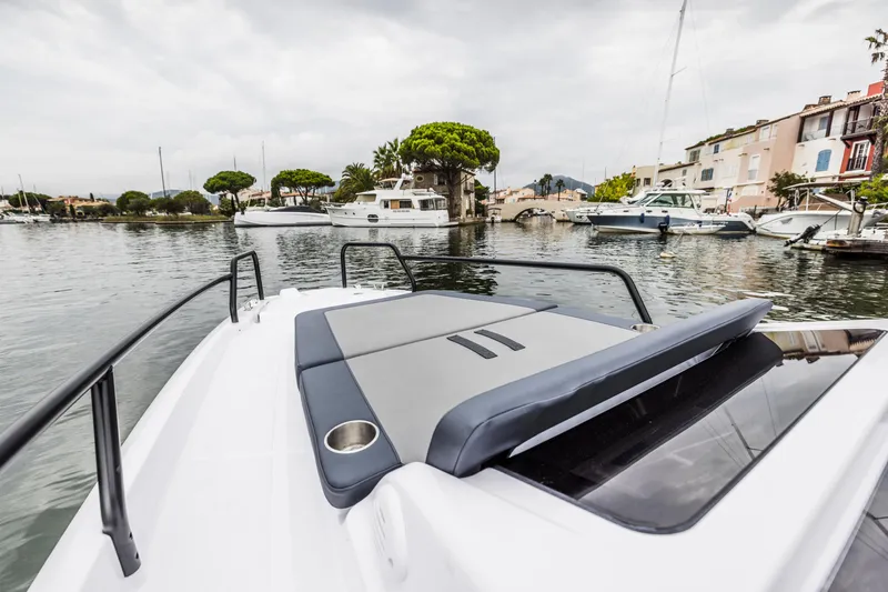 Slide: The Image of The 2023 Axopar 25 Cross Top is docked in a calm harbor with surrounding boats. - 5