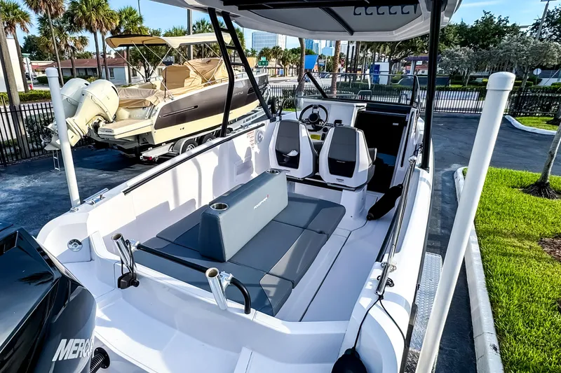 Slide: The Image of 2023 Axopar 25 Cross Top boat with sleek seating and modern design in a marina setting. - 5