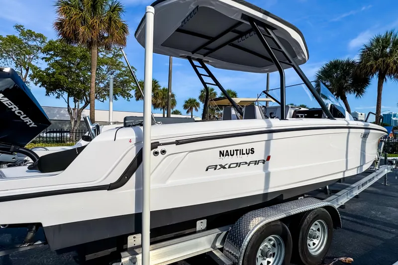 Slide: The Image of 2023 Axopar 25 Cross Top boat on trailer, surrounded by palm trees. - 3
