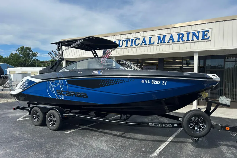 Slide: The Image of 2023 Scarab 255 Wake ID boat in blue and black, parked outside Nautical Marine. - 1