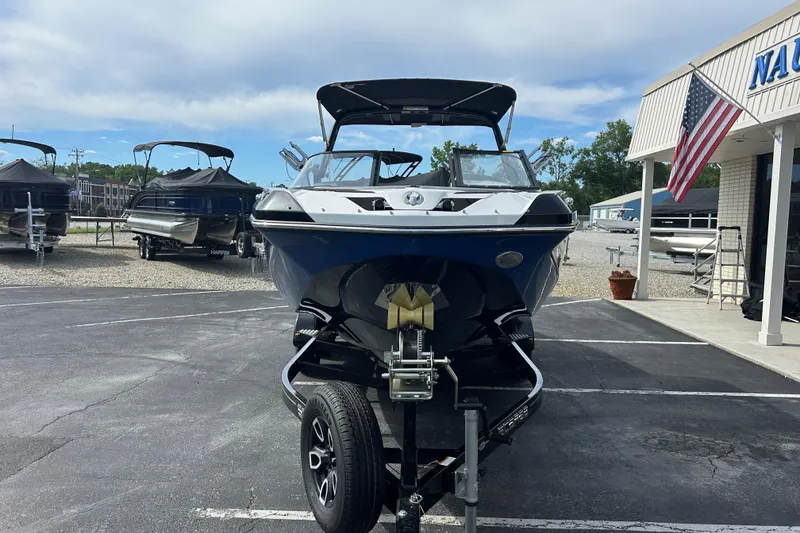 Slide: The Image of 2023 Scarab 255 Wake ID boat on trailer at dealership, surrounded by other boats. - 2
