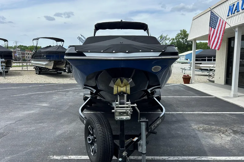 Slide: The Image of 2023 Scarab 255 Wake ID boat on trailer at dealership, American flag displayed. - 28