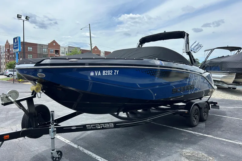 Slide: The Image of 2023 Scarab 255 Wake ID boat on trailer, parked in urban setting. - 29