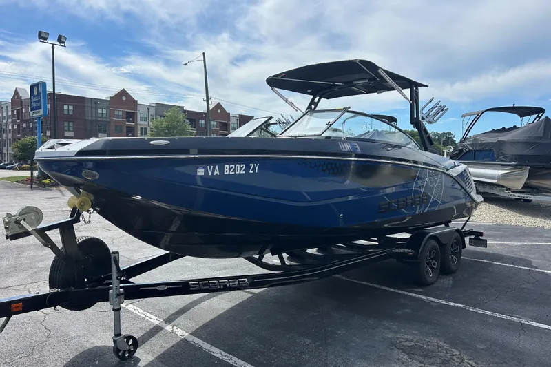 Slide: The Image of 2023 Scarab 255 Wake ID boat on trailer in parking lot, under clear sky. - 3