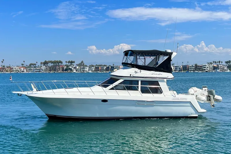 Slide: The Image of 1994 Navigator 4300 yacht cruising on a sunny day with coastal homes in the background. - 2