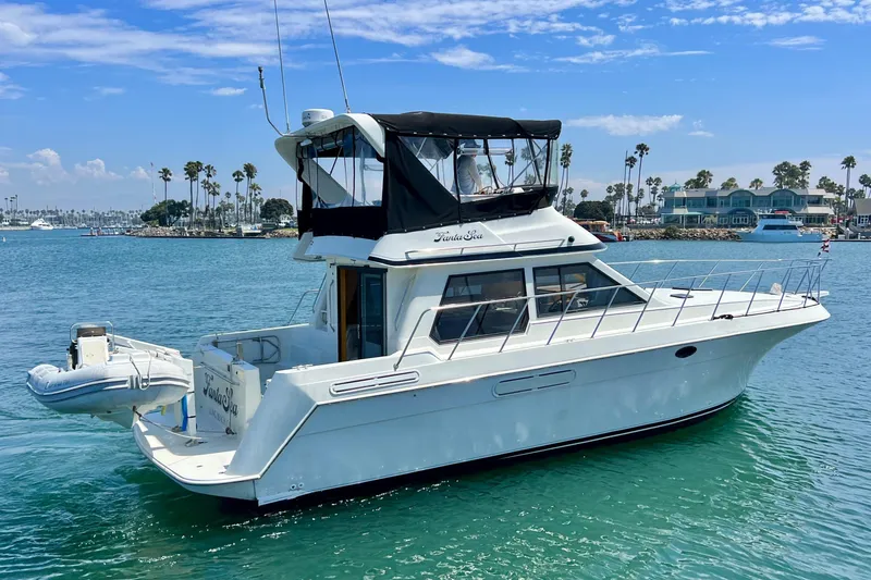 Slide: The Image of 1994 Navigator 4300 yacht on calm water, featuring a flybridge and scenic coastal backdrop. - 4