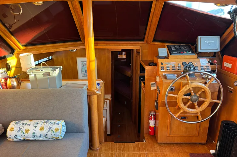 Slide: The Image of Cozy 1987 President 37 yacht interior with wooden helm, seating, and navigation equipment. - 13