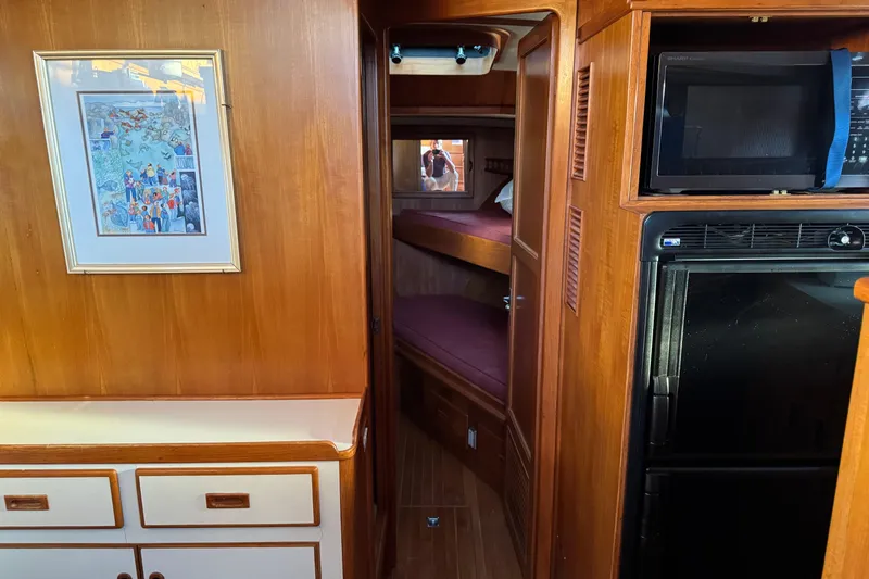 Slide: The Image of Interior of a 1987 President 37 yacht with wood paneling, bunk beds, and kitchen appliances. - 26