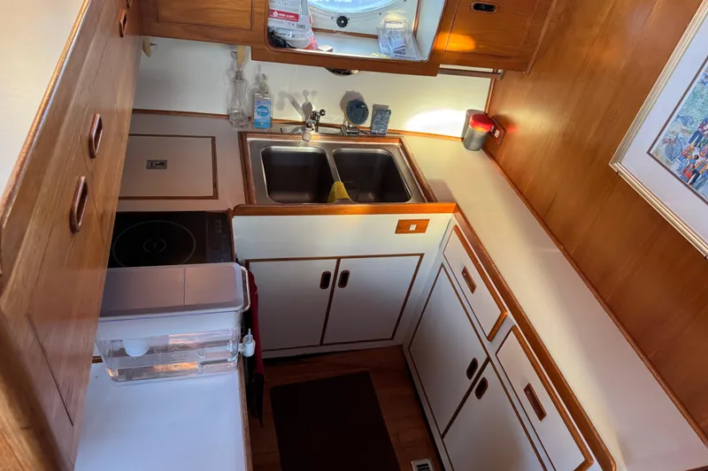 Slide: The Image of Compact kitchen in a 1987 President 37 boat with wooden cabinetry and dual sinks. - 27