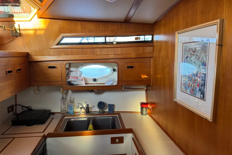 Slide: The Image of Wood-paneled kitchen interior of 1987 President 37 yacht with framed artwork and porthole window. - 34