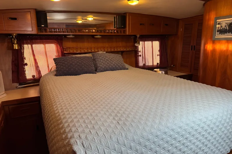 Slide: The Image of Cozy bedroom in a 1987 President 37 RV with quilted bedding and wooden cabinetry. - 46