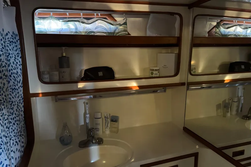 Slide: The Image of 1987 President 37 yacht bathroom with sink, mirror, and toiletries on shelves. - 55