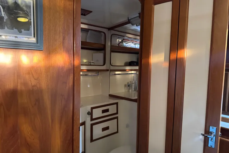 Slide: The Image of Wood-paneled bathroom interior of a 1987 President 37 yacht, featuring storage cabinets and a mirror. - 56