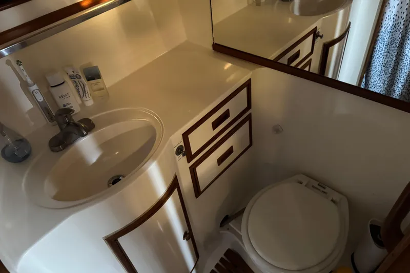 Slide: The Image of Compact bathroom in a 1987 President 37 yacht, featuring sink, mirror, and toilet. - 57
