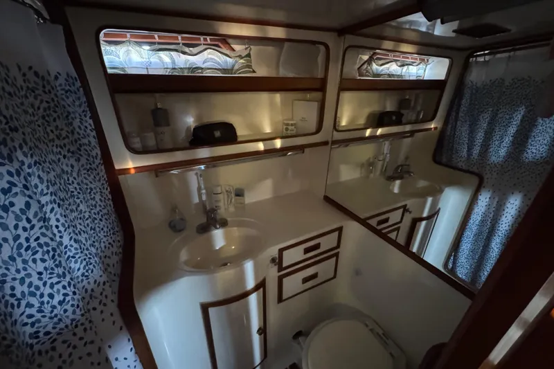 Slide: The Image of 1987 President 37 yacht bathroom with sink, mirror, and patterned shower curtain. - 58