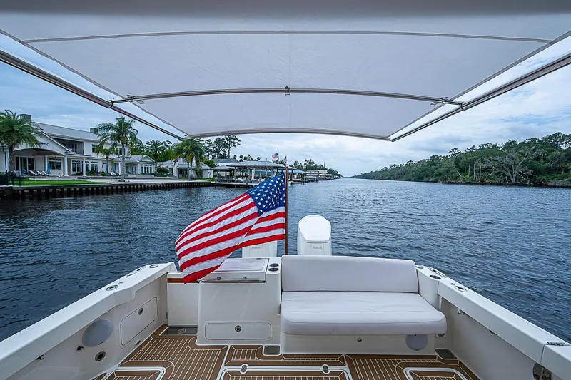 Slide: The Image of 2023 Hinckley Sport Boat 40 X cruising on a scenic river with American flag. - 5