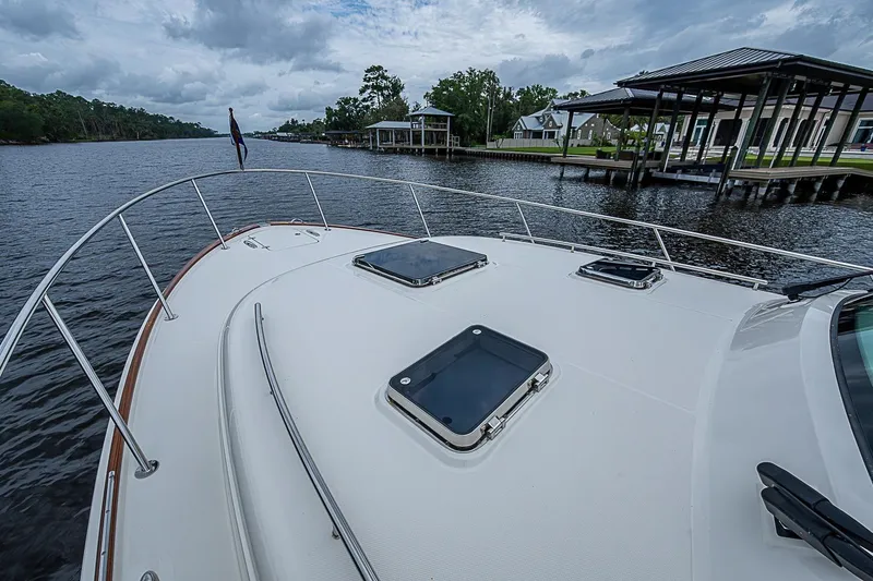 Slide: The Image of 2023 Hinckley Sport Boat 40 X on a serene river with docks and trees. - 16