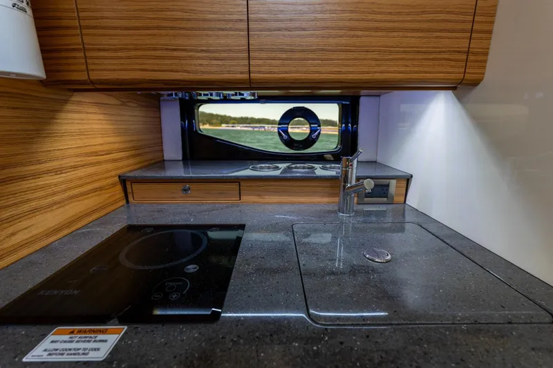 Slide: The Image of Modern kitchen area in 2023 Boston Whaler 405 Conquest boat, featuring sleek countertops and wood cabinetry. - 18