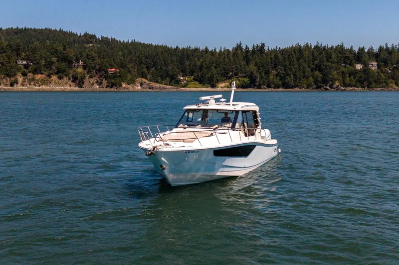 Slide: The Image of 2023 Boston Whaler 405 Conquest cruising on a scenic lake with forested shoreline. - 4