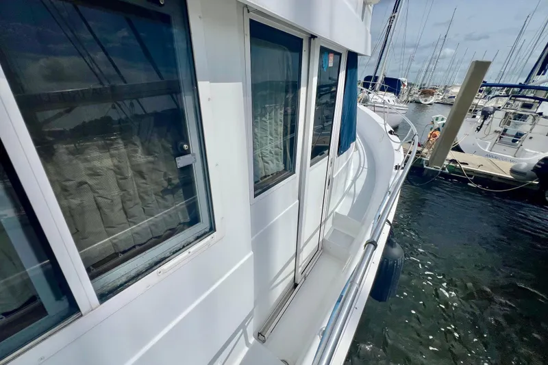 Slide: The Image of 1999 Mainship 350 Trawler docked at marina, showcasing side view and windows. - 11