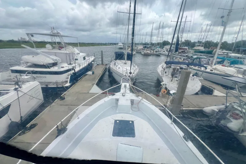 Slide: The Image of 1999 Mainship 350 Trawler docked among sailboats at a marina under cloudy skies. - 15