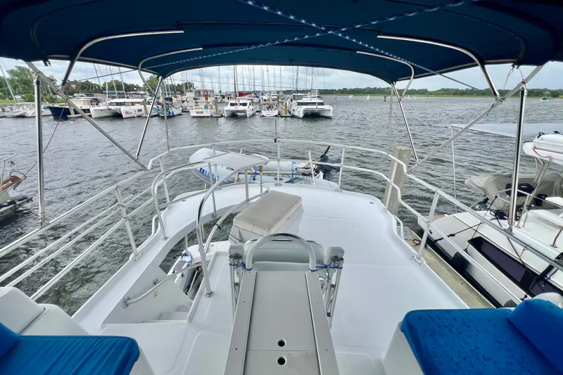 Slide: The Image of 1999 Mainship 350 Trawler docked at marina, featuring spacious deck and blue canopy. - 19