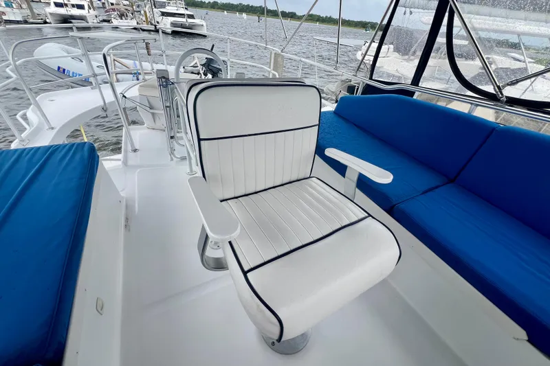 Slide: The Image of 1999 Mainship 350 Trawler helm area with white captain's chair and blue seating. - 24
