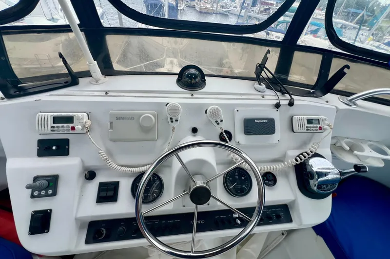 Slide: The Image of 1999 Mainship 350 Trawler helm with steering wheel, navigation equipment, and marine radios. - 25