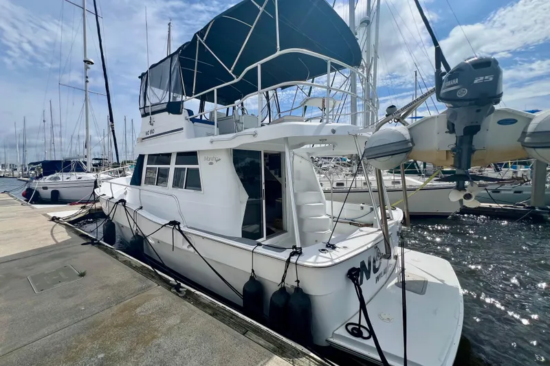 Slide: The Image of 1999 Mainship 350 Trawler docked at marina, featuring upper deck and Yamaha outboard motor. - 3
