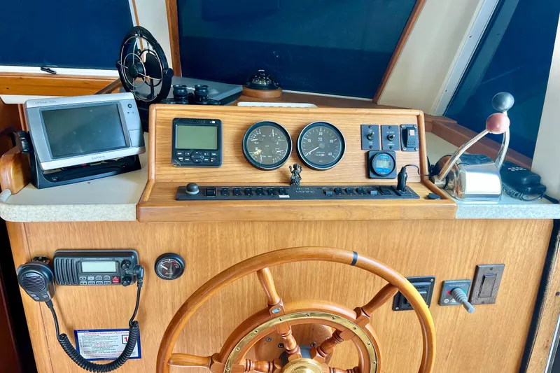 Slide: The Image of 1999 Mainship 350 Trawler helm with navigation instruments and wooden steering wheel. - 32