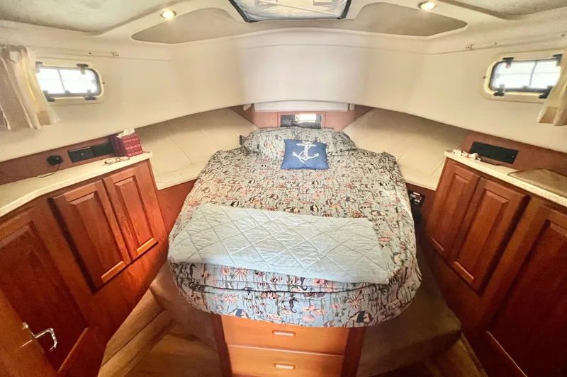 Slide: The Image of 1999 Mainship 350 Trawler cabin interior with cozy bed and wooden cabinetry. - 35