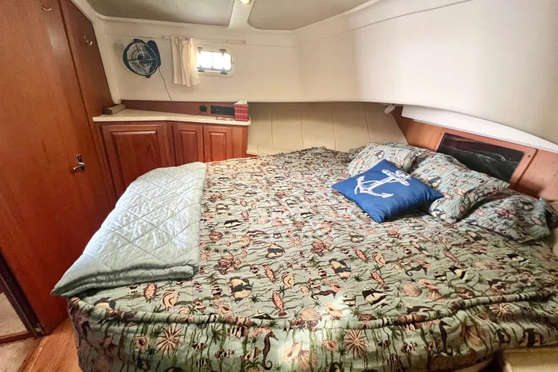 Slide: The Image of Cozy bedroom in 1999 Mainship 350 Trawler with nautical-themed bedding and wooden cabinetry. - 36