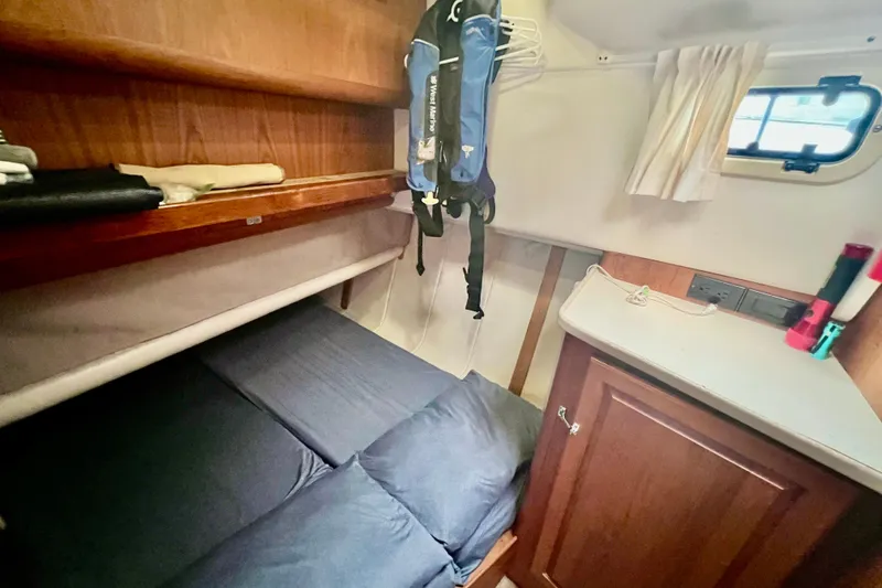 Slide: The Image of Cozy cabin interior of 1999 Mainship 350 Trawler with bed, storage, and window. - 40