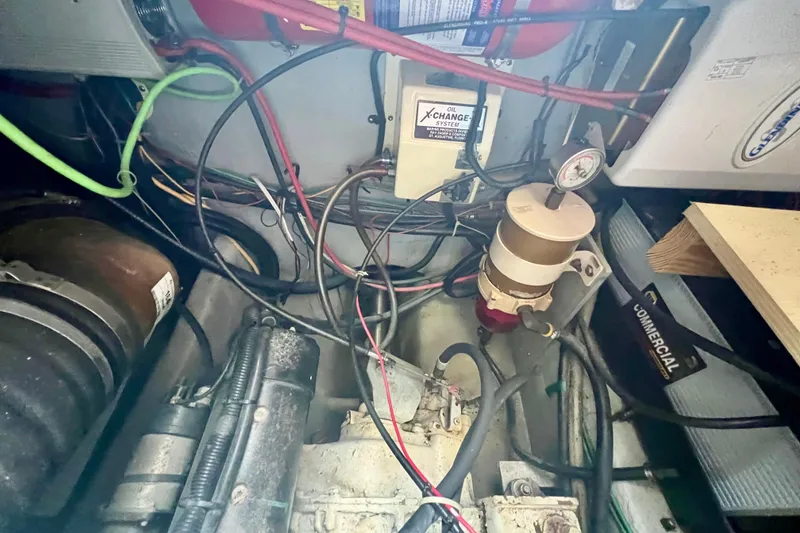 Slide: The Image of Engine room of a 1999 Mainship 350 Trawler with wiring and oil system components. - 44