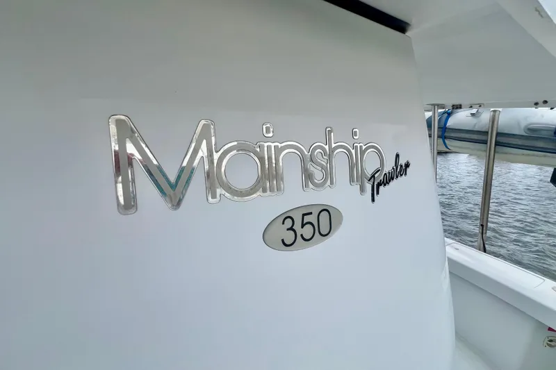 Slide: The Image of Mainship 350 Trawler 1999 logo on boat exterior near water. - 55
