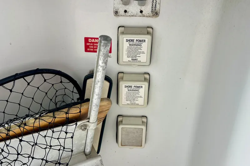 Slide: The Image of Shore power outlets and warning labels on a 1999 Mainship 350 Trawler boat. - 8