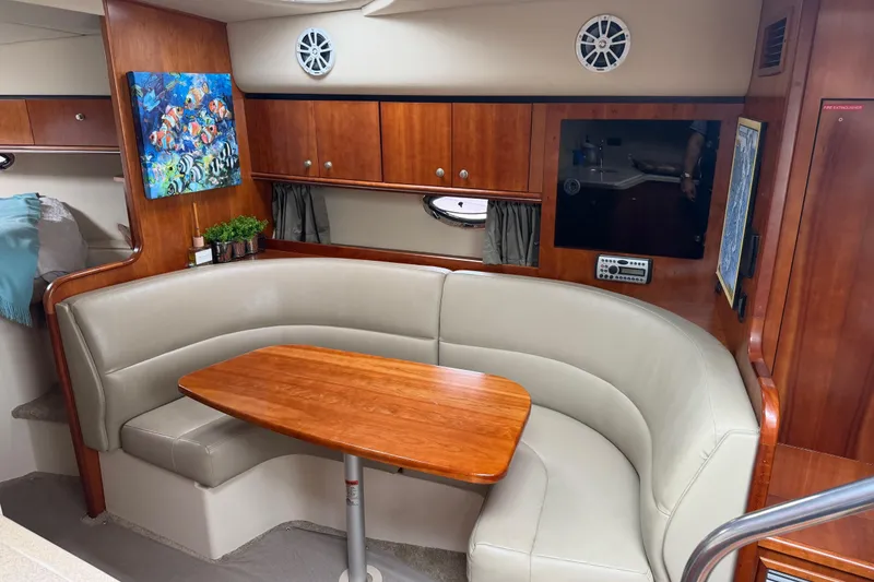 Slide: The Image of Interior of 2007 Cruisers 340 Express yacht with curved seating and wooden table. - 23