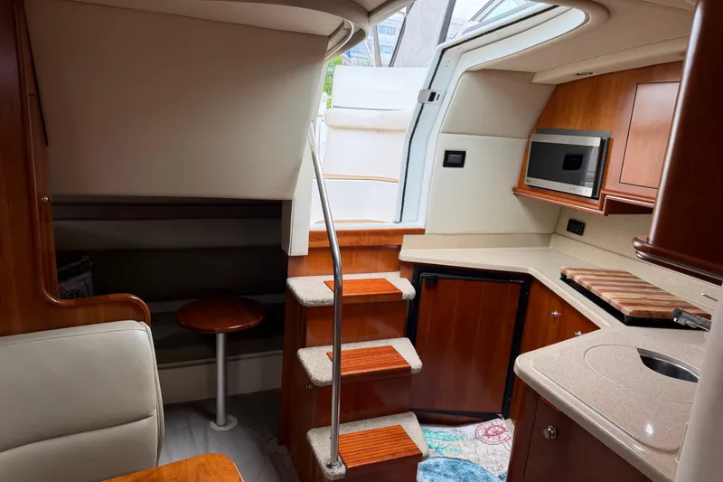 Slide: The Image of 2007 Cruisers 340 Express cabin interior with kitchenette, stairs, and seating area. - 33