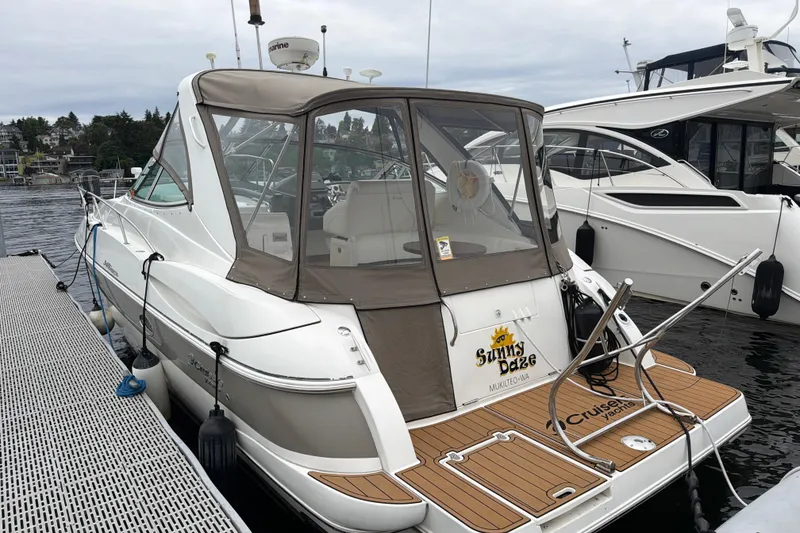 Slide: The Image of 2007 Cruisers 340 Express yacht docked, featuring a covered cockpit and teak swim platform. - 56