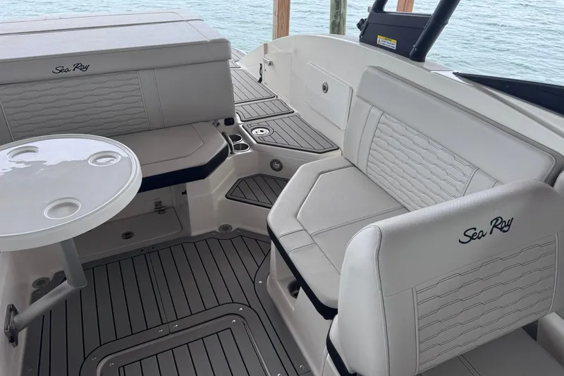Slide: The Image of 2021 Sea Ray SPX 230 boat interior with white seating and round table on water. - 14