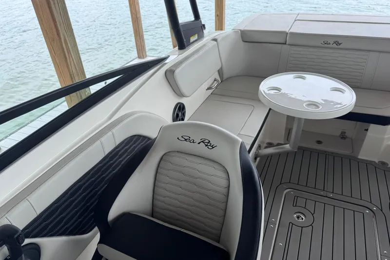 Slide: The Image of 2021 Sea Ray SPX 230 boat interior with seating and table, dockside view. - 18