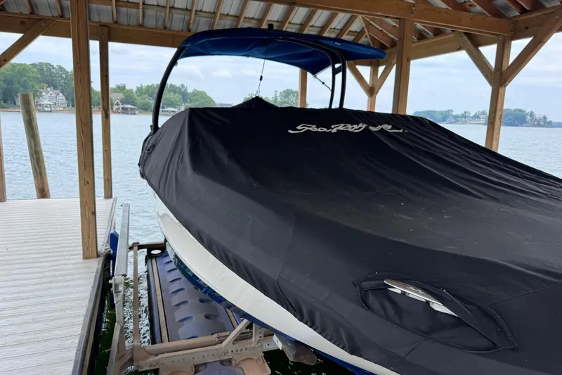 Slide: The Image of 2021 Sea Ray SPX 230 boat covered and docked under a wooden shelter by the lake. - 4