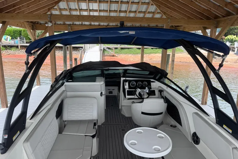 Slide: The Image of 2021 Sea Ray SPX 230 boat interior with seating and dashboard under a dock canopy. - 10
