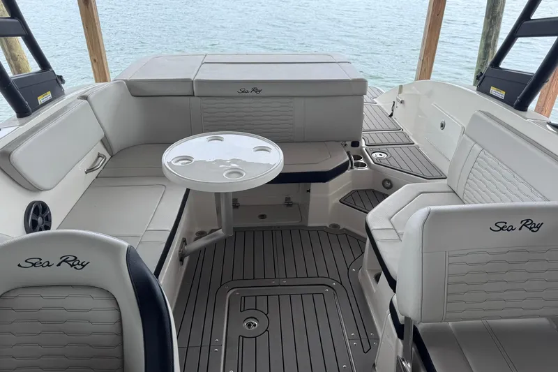 Slide: The Image of 2021 Sea Ray SPX 230 boat interior with seating and table, overlooking water. - 11