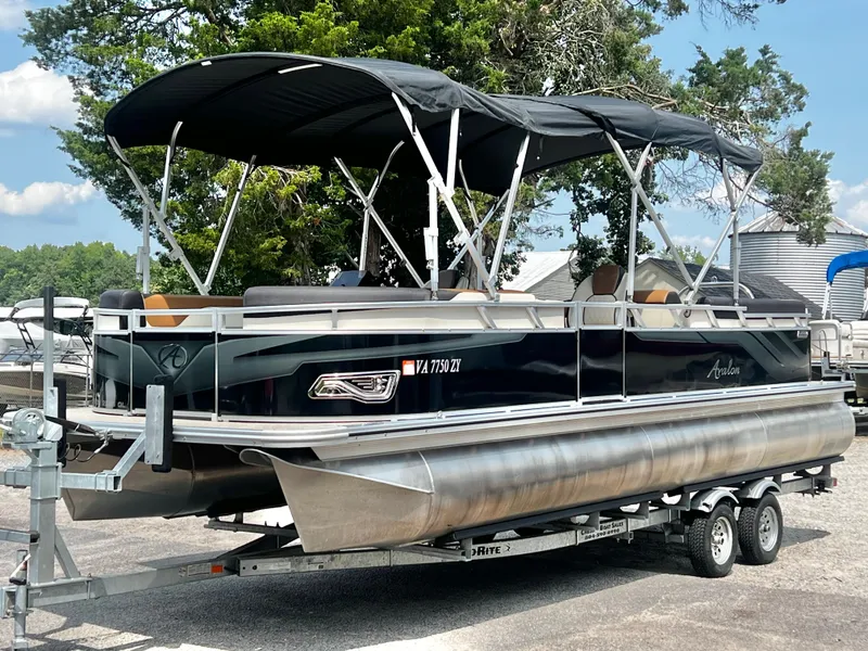 The Image of 2023 Avalon Venture 85 25' Quad Lounge on a trailer, featuring a black canopy and sleek seating. - 1