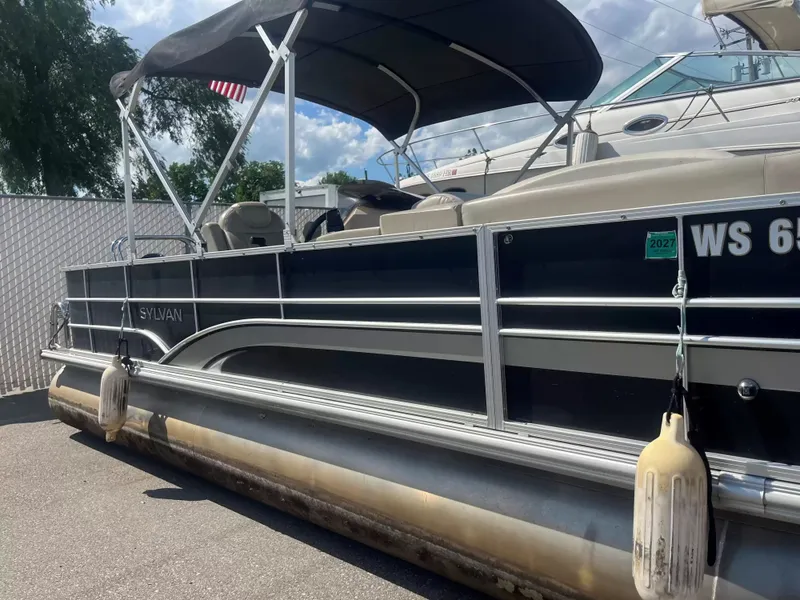 The Image of A 2015 Sylvan 8522 CNF pontoon boat with a canopy, fenders, and side railing. - 1