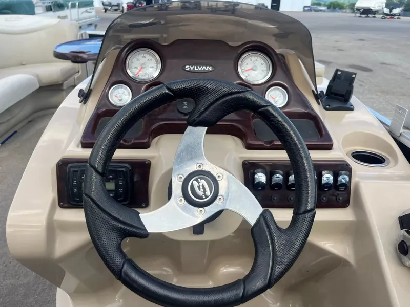 Slide: The Image of The image shows the helm of a 2015 Sylvan 8522 CNF boat with multiple gauges. - 12